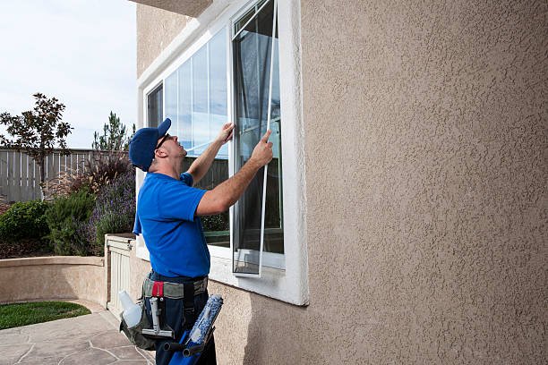man cleaning window of a home and installing a screen,