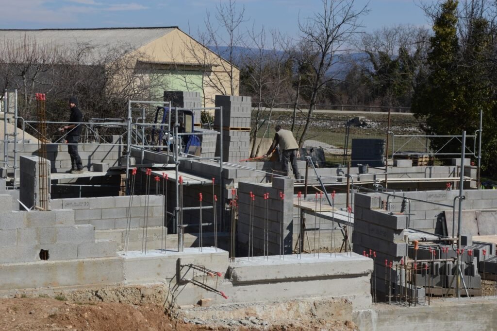 Construction workers building a concrete structure at a sunlit site.