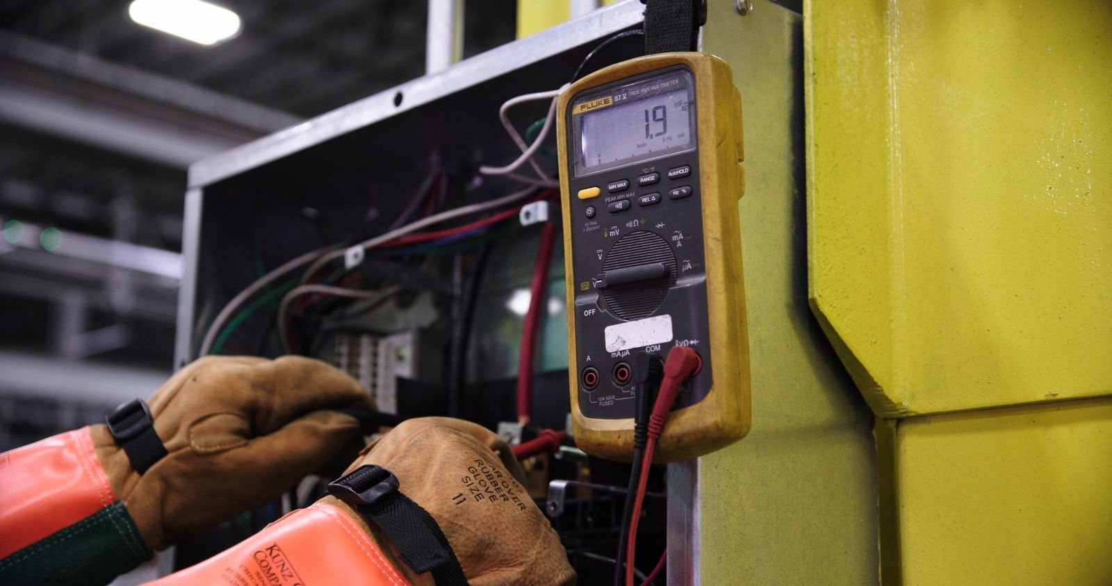 Artisans et métiers du bâtiment à Paris et en Île-de-France Homme réparant un boîtier électrique avec des outils – Électricien dans le Val-d'Oise (95)