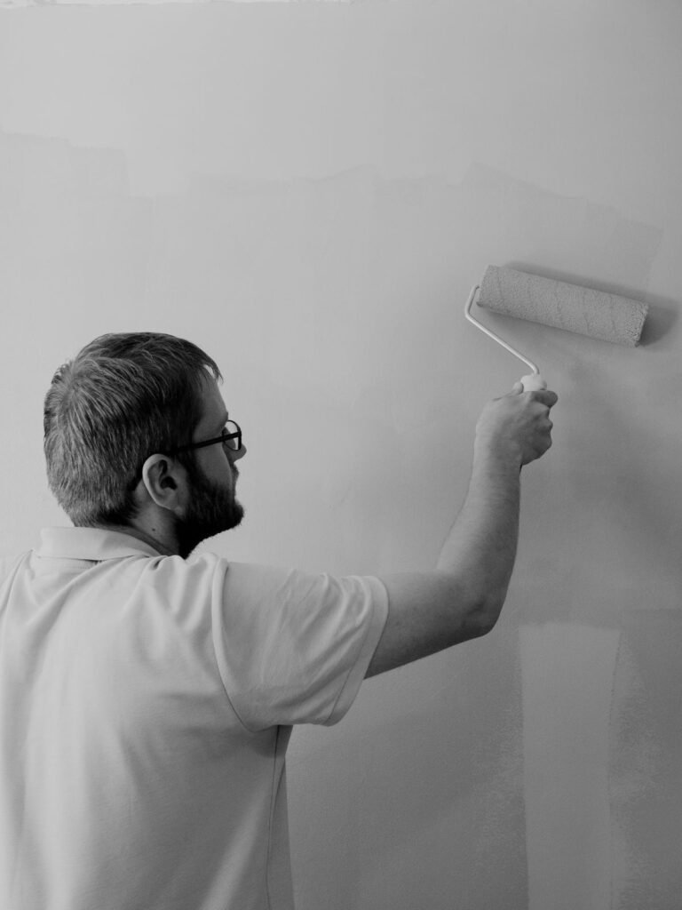 Homme peignant un mur intérieur au rouleau à peinture