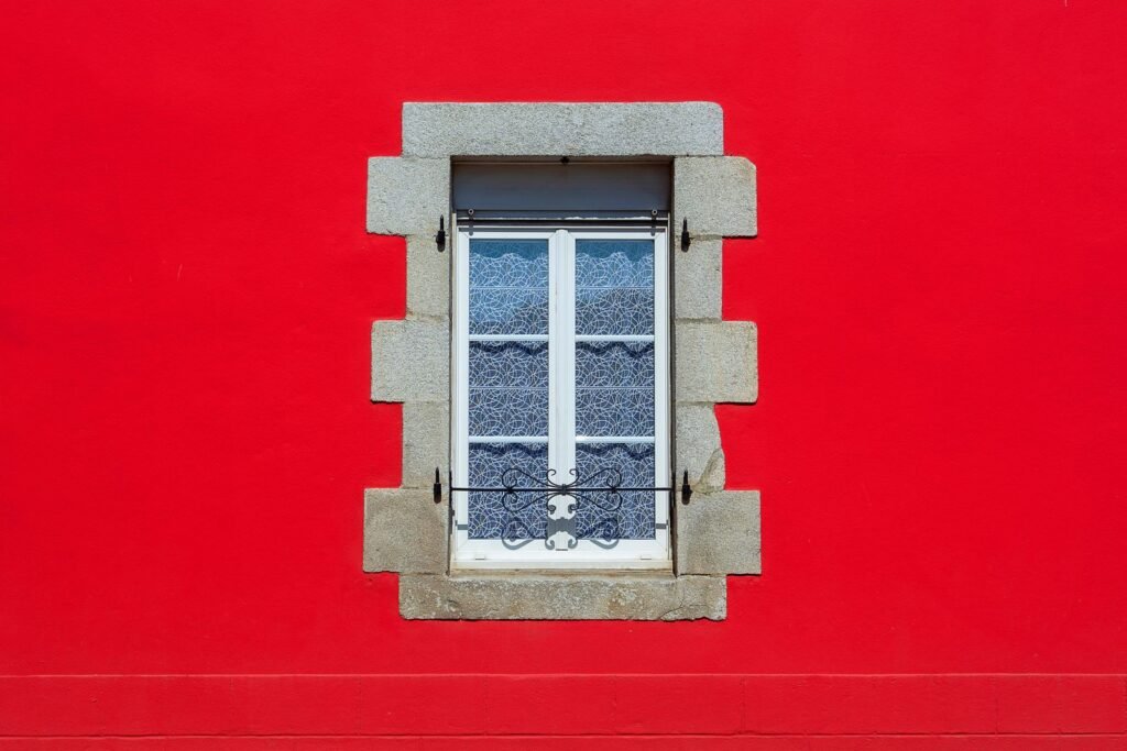 Fenêtre à cadre blanc sur un mur de maison rouge
