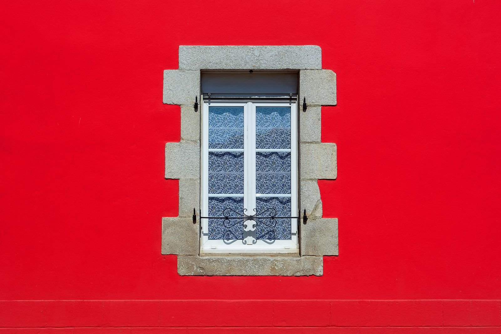 Artisans et métiers du bâtiment à Paris et en Île-de-France Fenêtre à cadre blanc sur un mur de maison rouge – Devis plombier dans les Hauts-de-Seine (92)