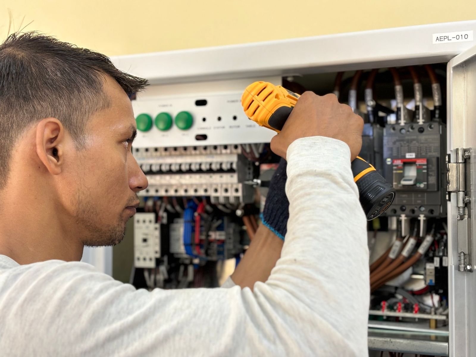 Artisans et métiers du bâtiment à Paris et en Île-de-France Homme travaillant sur un tableau électrique professionnel – Électricien en Seine-Saint-Denis (93)