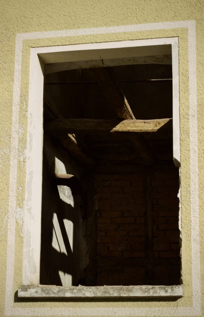 Ancien mur en briques vu à travers une fenêtre cassée