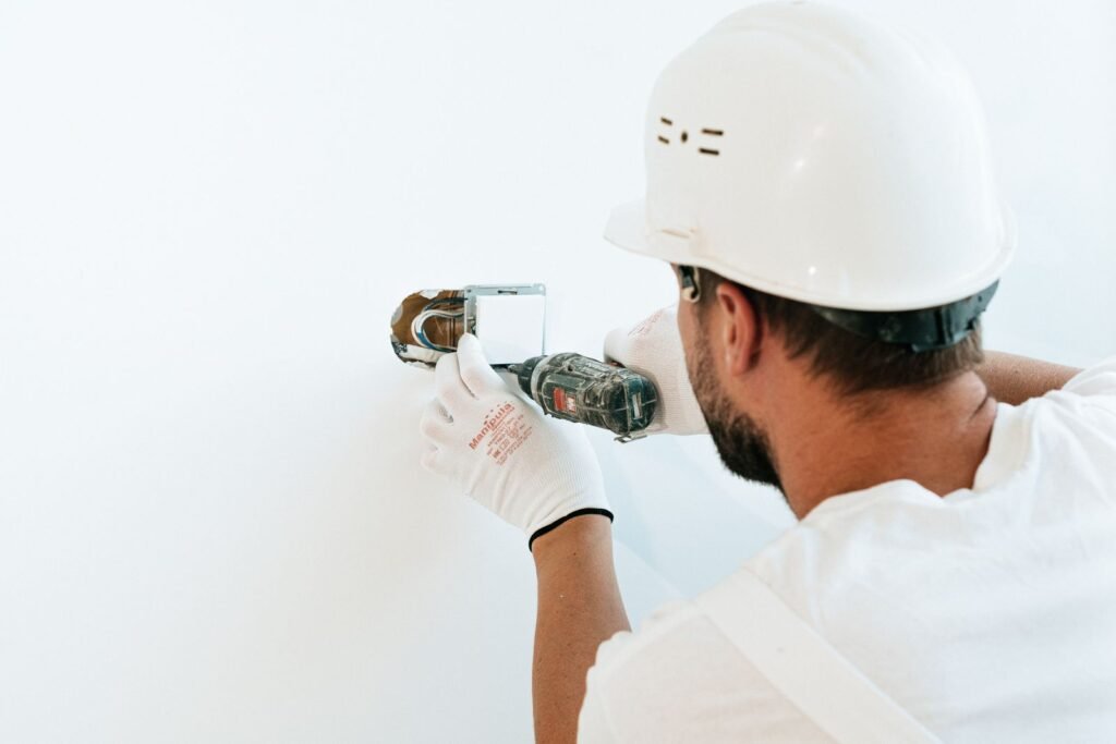 Homme réparant un interrupteur mural électrique