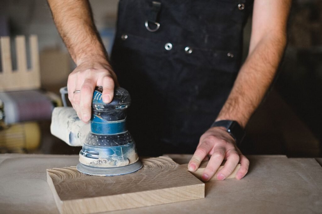 Artisan poncant une planche de bois